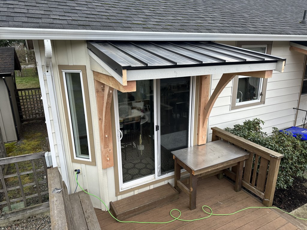 Standing seam metal awning on timber brackets built over a rear patio door