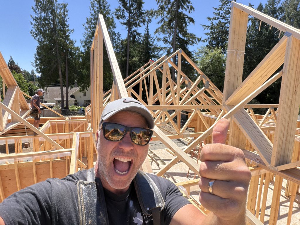 Smiling VIP Homes carpenter giving a thumbs up amid new wall framing