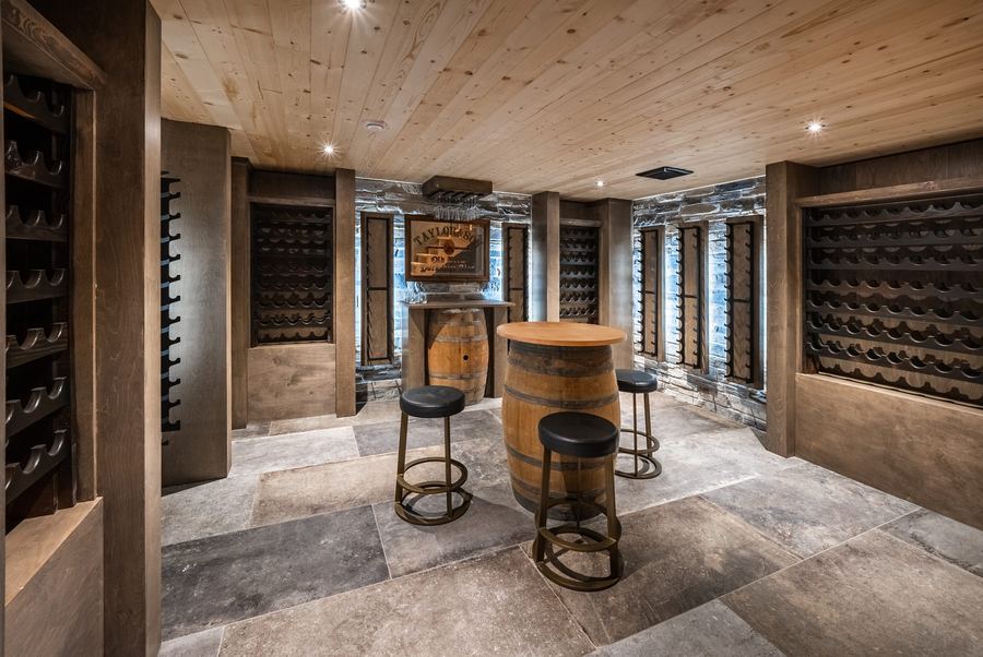 Custom wine cellar with barrel seating, stone floors and full-height racking