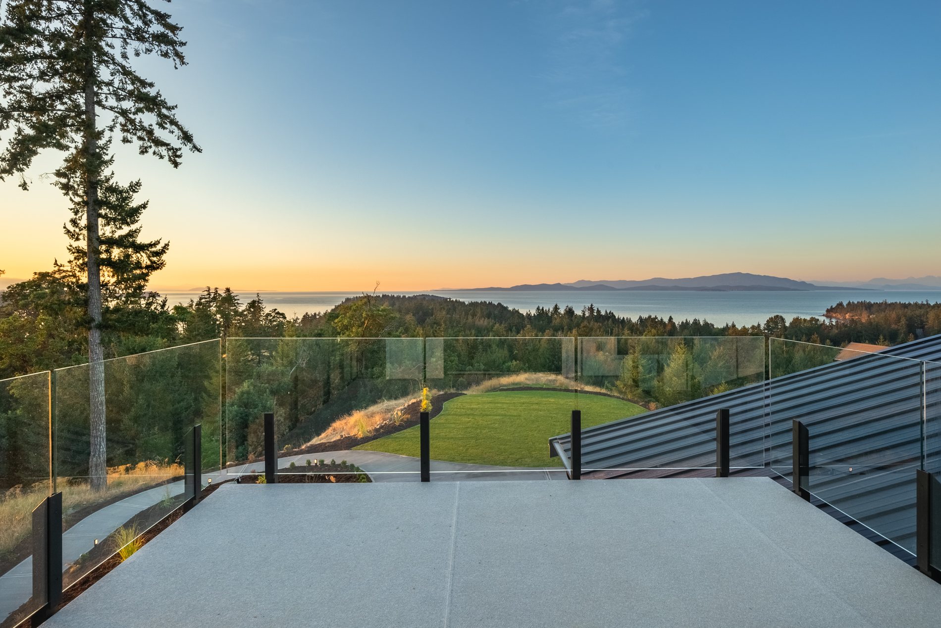 Sunset over the water from the glass railed deck of a custom home built by VIP Homes
