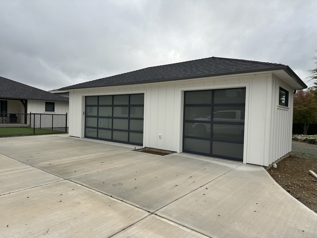 Detached double garage with glass panel doors and a new concrete apron