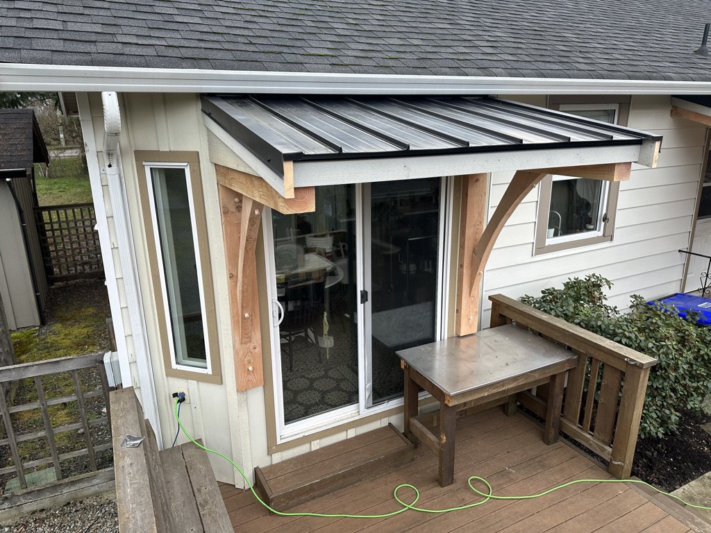Standing seam metal awning and timber brackets over a rear patio door