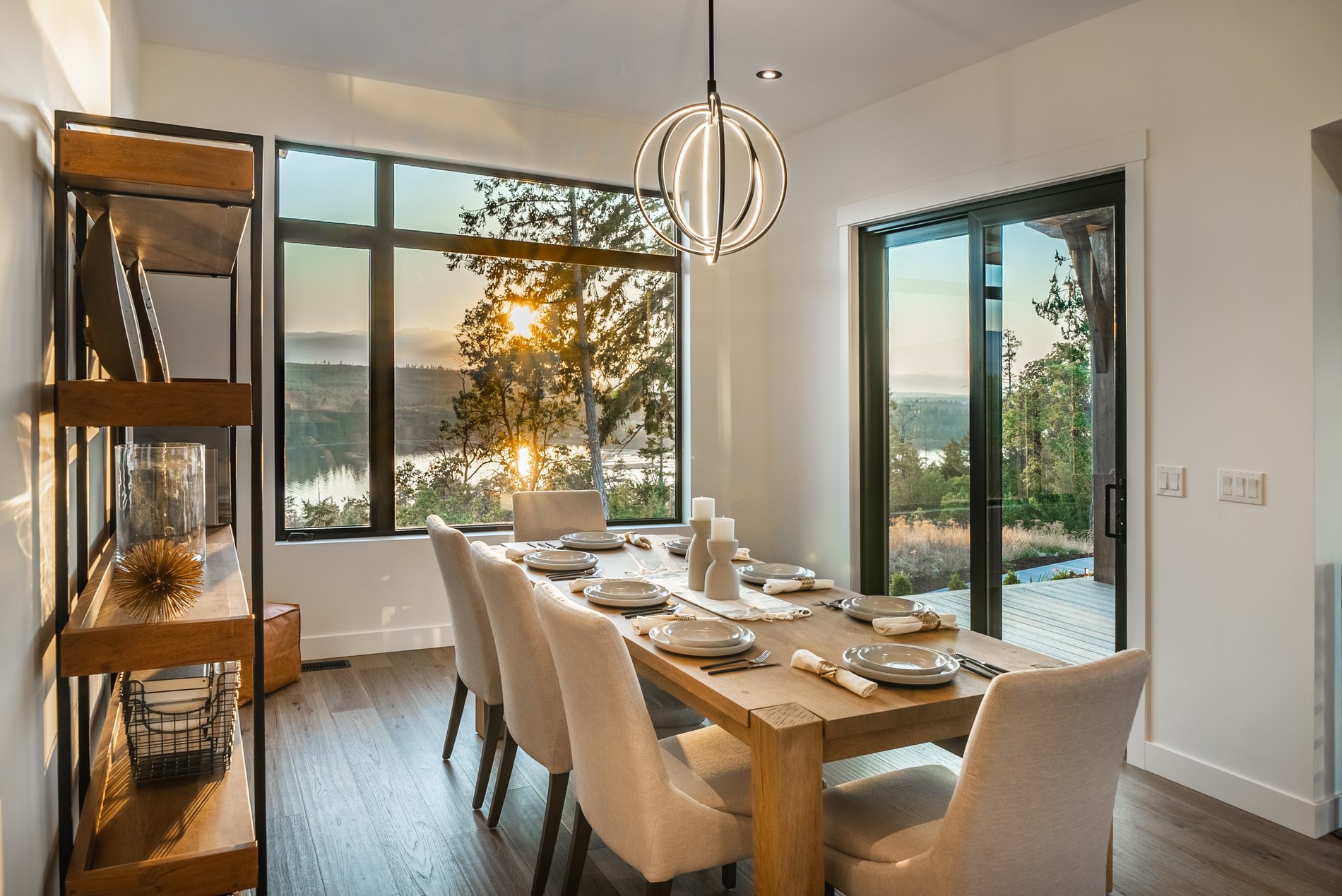 Dining area with a timber table beside floor to ceiling windows looking out to the ocean