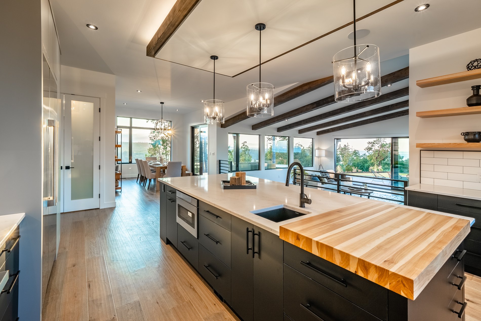 Custom kitchen with a live edge walnut island, black cabinetry and exposed beams