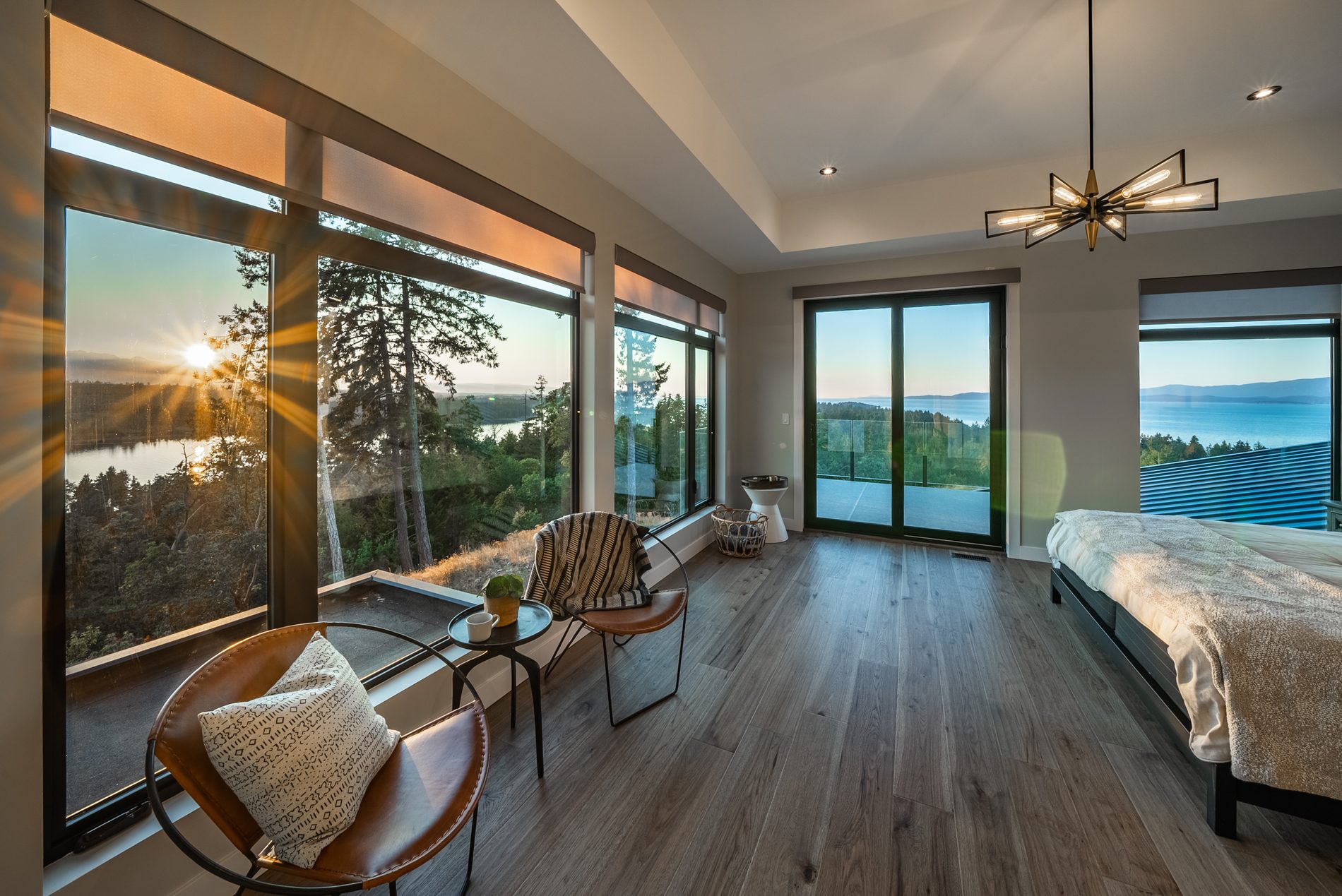 Primary bedroom with wide plank floors and a sunset view over the water