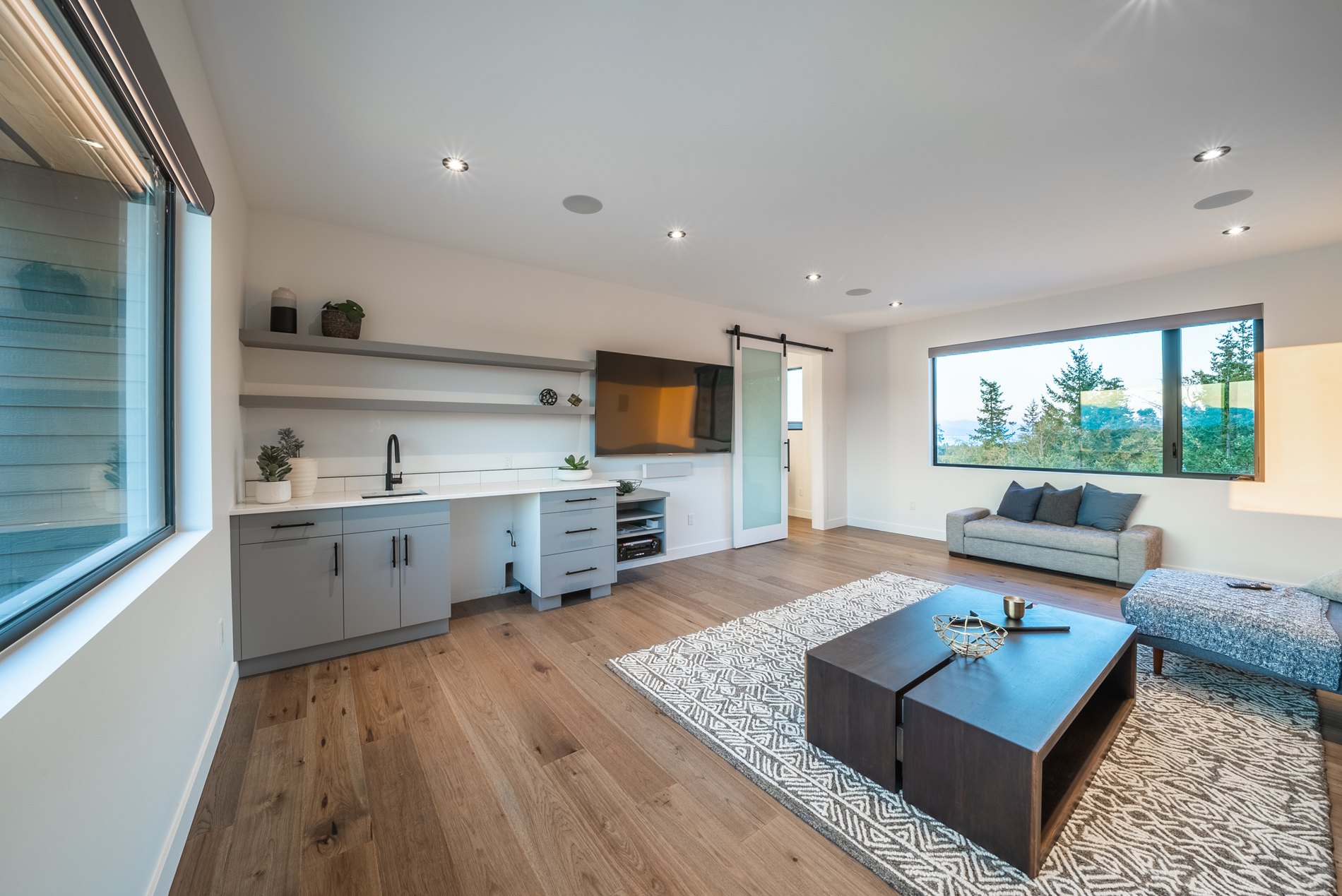 Open living and kitchenette area with wide plank floors and a barn door