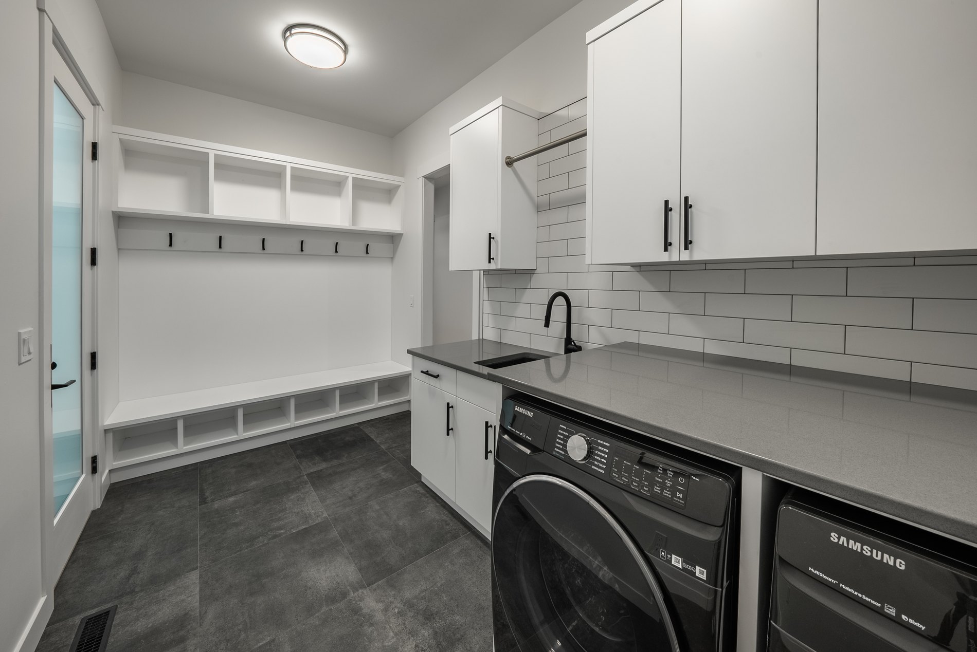 Mudroom and laundry with a bench, hooks and a stacked washer and dryer