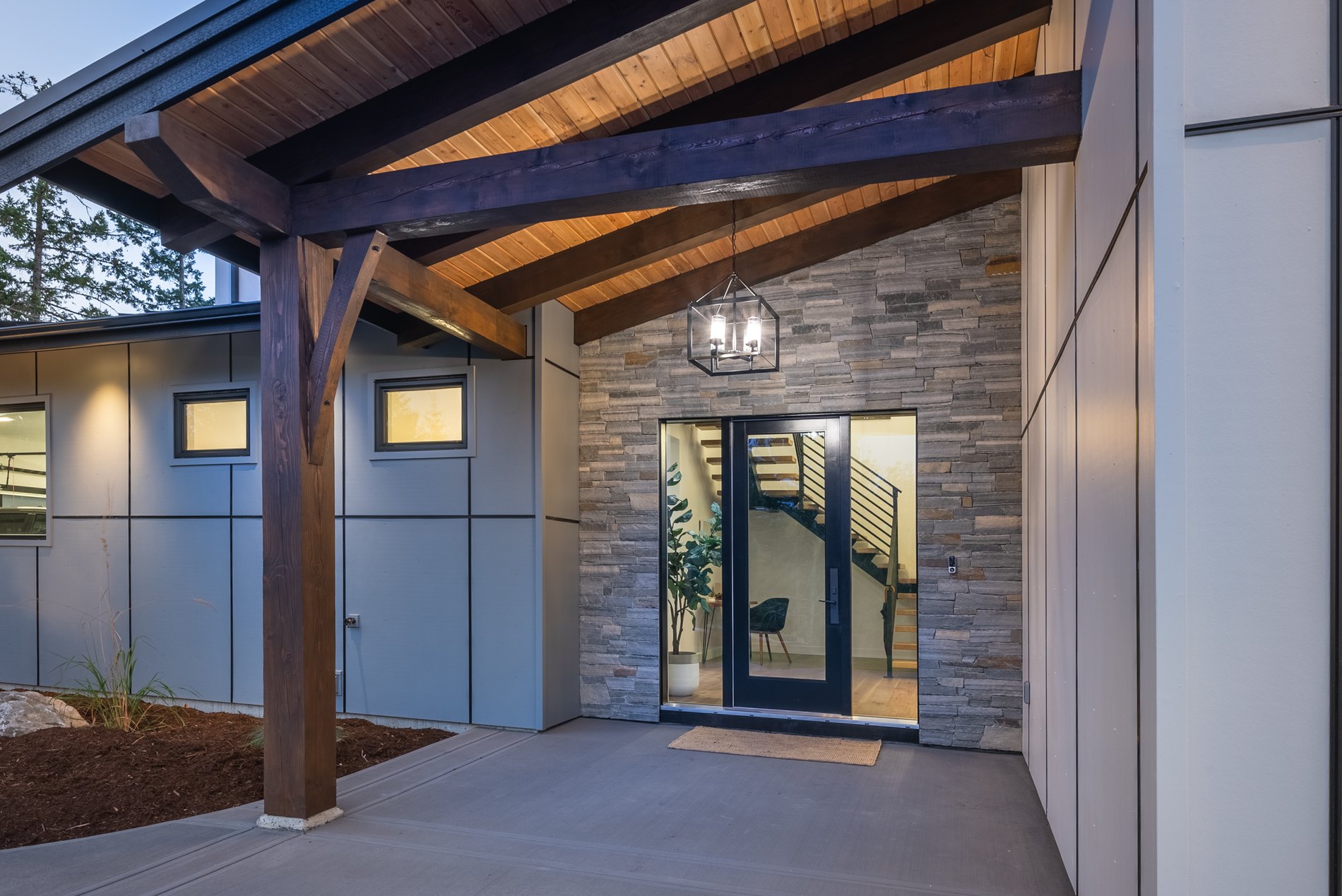 Covered front entry with timber posts, stone cladding and a glazed door