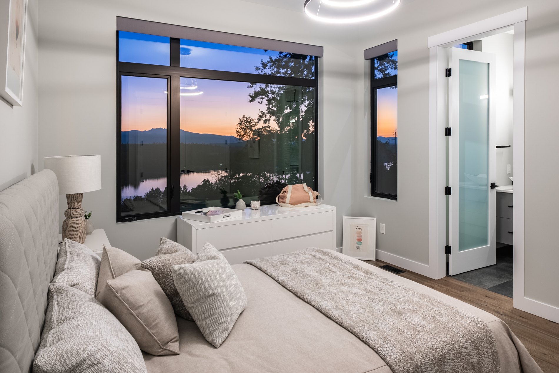 Bedroom with a large window framing the ocean and morning light