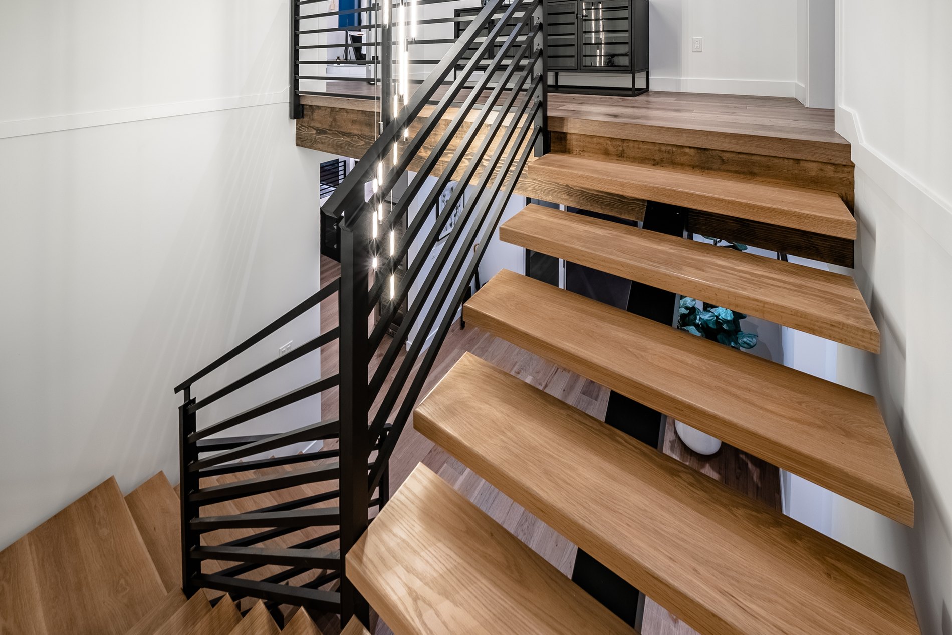 Detail of oak stair treads and a black steel railing